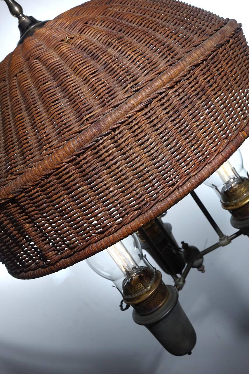 This is an early wicker shade in excellent original condition with only a couple of small nicks in the weave here and there. I was told that the shade may even be Stickley. The fixture is a three-light oil lamp that has been wired to take standard