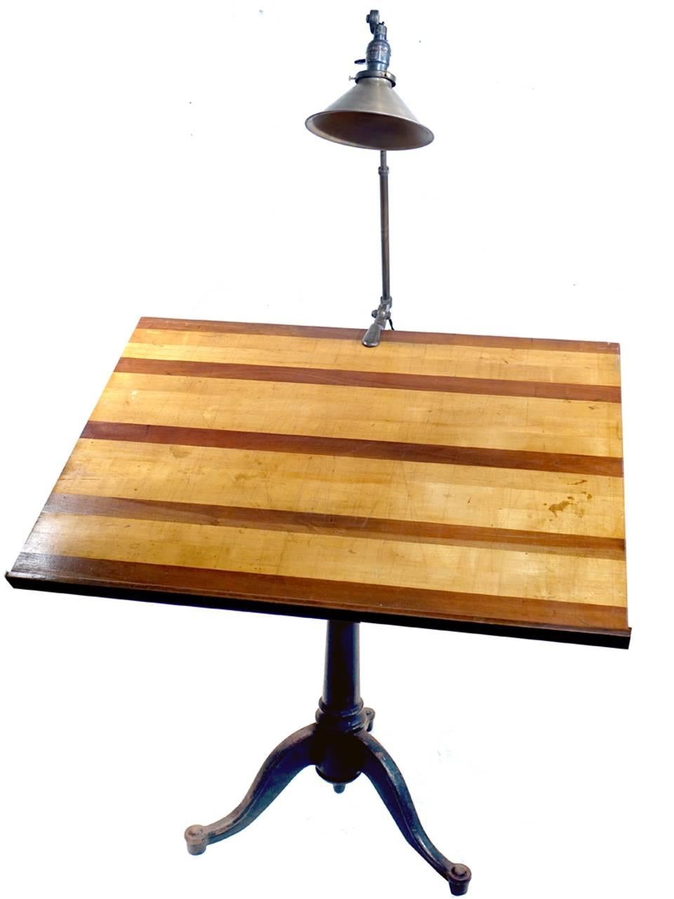 This is the quintessential architects drawing table. An articulating cast iron base and a beautiful contrasting wood drawing board. The table turns, moves up and down and tilts. In addition it comes with a beautiful and very sought after all brass
