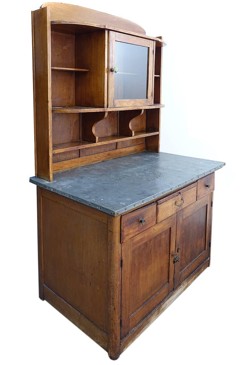 The smaller scale, glass display cabinet and sink top give this piece its charm. In the cabinet below there is a tilt out compartment that I believe was used to hold dough for baking. The metal top would also be perfect for preparing bread. It has a