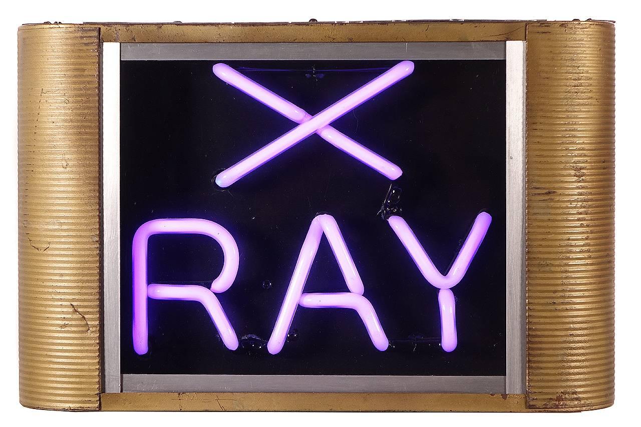 This sign looks to be 1930s, It sits in a glass window tin casing with rounded ends. The neon glows a striking lavender. The case also has two loops for hanging from wire and cutouts to wall hang.