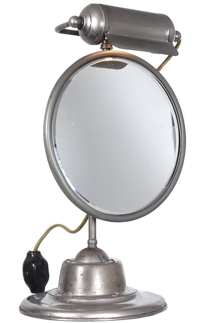 This is a nicely detailed make-up or shaving mirror. It looks to be all business with no decorative elements but lots of character. The base has an oversized articulating ball and the light is a horizontal shade not unlike an art lamp. It is mostly