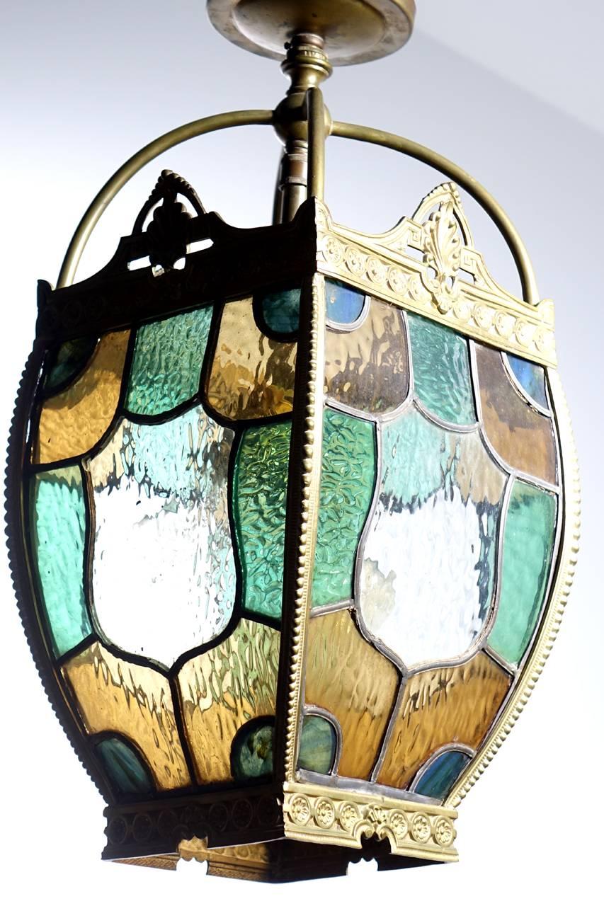 This Tudor style lamp is perfect for a front entrance, stair or hall. The medallion centered curved glass looks beautiful with or without light. Its all framed in detailed stamped brass.