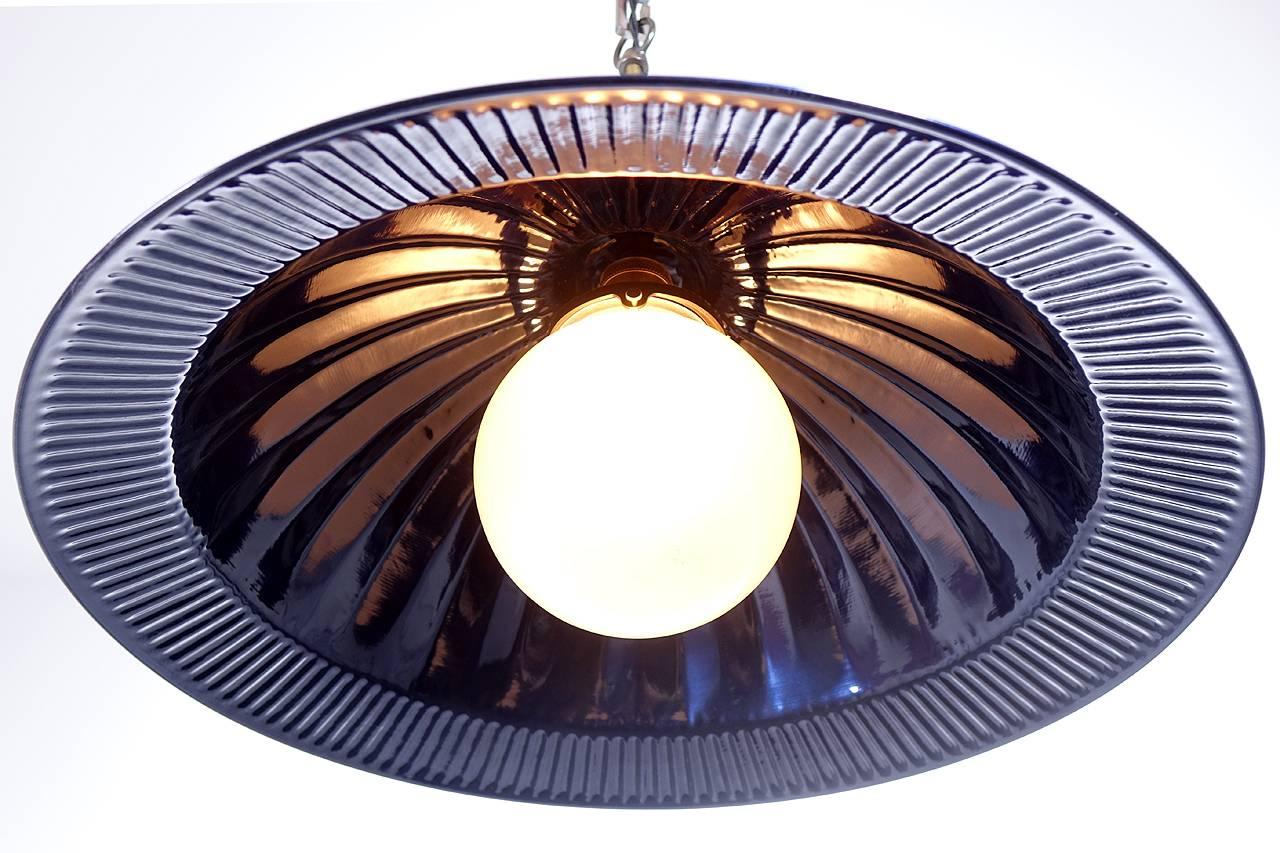 These large dramatic original domes have a 20 inch diameter. There is a dramatic pleated pattern that curves over the top and a flared ribbed edge. We restored these lamps in a hard baked on powder coat finish. The color is a cobalt blue black that