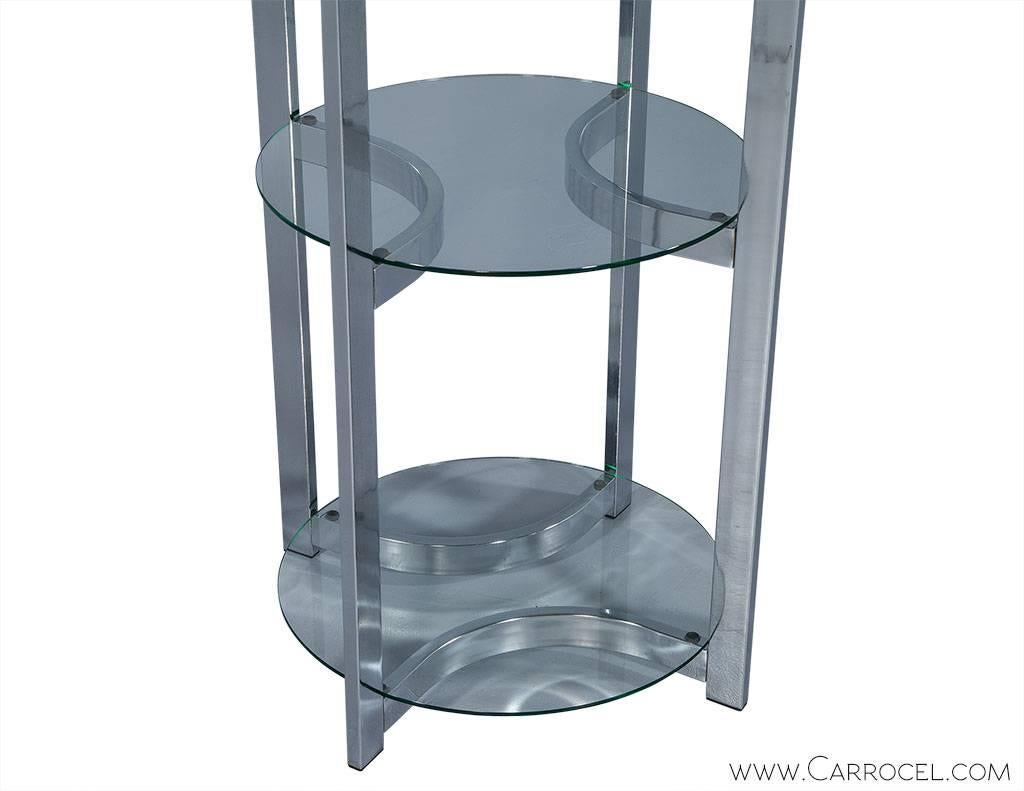Late 20th Century display shelf takes on an interesting appeal housing round pieces of polished edged glass shelves stacking vertically on a polished chrome frame. At six feet tall this is an eye grabbing display that can be seen from all directions.