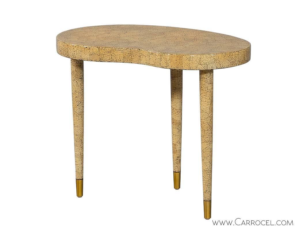 These vintage inspired accent tables, designed by Aerin provide the perfect drop of flare. Small proportions are packed with taste, featuring kidney shaped tops covered in taupe craquelure finish, standing on turned tapered legs capped in brass. Let