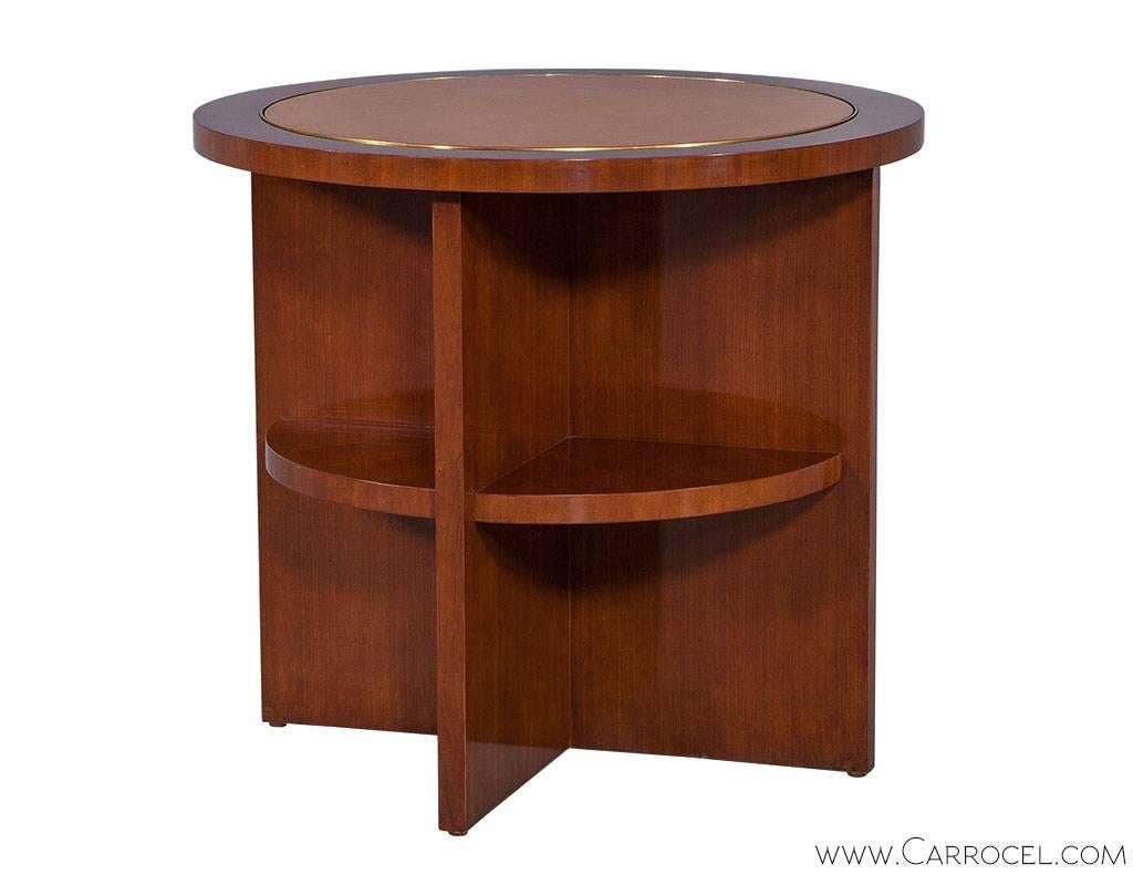 A decadent occasional table designed by Ralph Lauren plays with fusing a palette of materials; a yellow leather top, edged with polished brass is inset into warm mahogany. The base provides 360 degree display with a lower circular shelf inset into