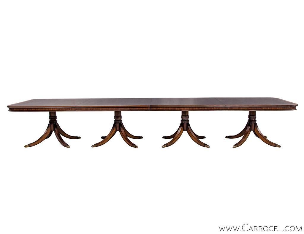 This grandiose flamed mahogany banquet table comes with elaborate workmanship in the form of satinwood, tulipwood and ribbon mahogany inlays on the table top, and spider leg pedestals terminating in claw feet in typical Duncan Phyfe fashion.