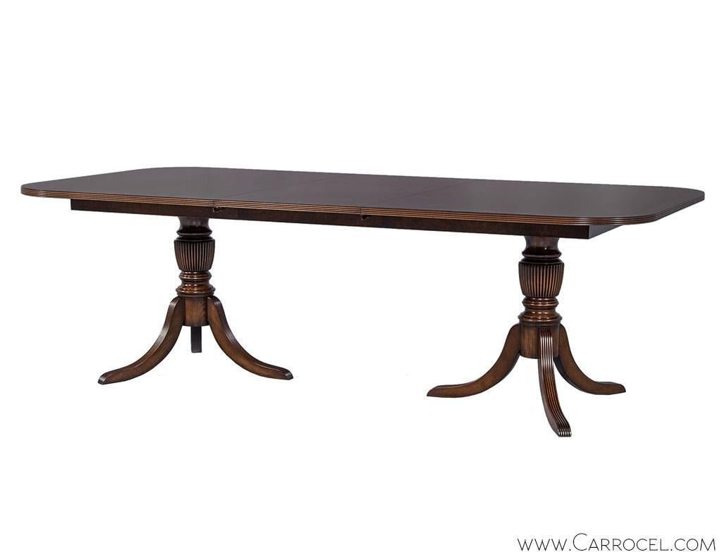 Classic flamed mahogany English Duncan Phyfe style dining table finished in house by Carrocel craftsmen in our custom Imperial Ember satin finish with a contrasting enriched satinwood banding. Table includes two extension leaves measuring W: 22”