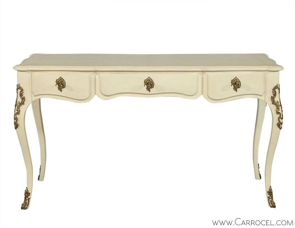 Designed by Ralph Lauren, this beautiful Louis XV desk will carry grace and traditional style into your home. With elegant curves throughout, the desk features a scalloped top, saber legs decorated with brass corner and feet mounts, decorative