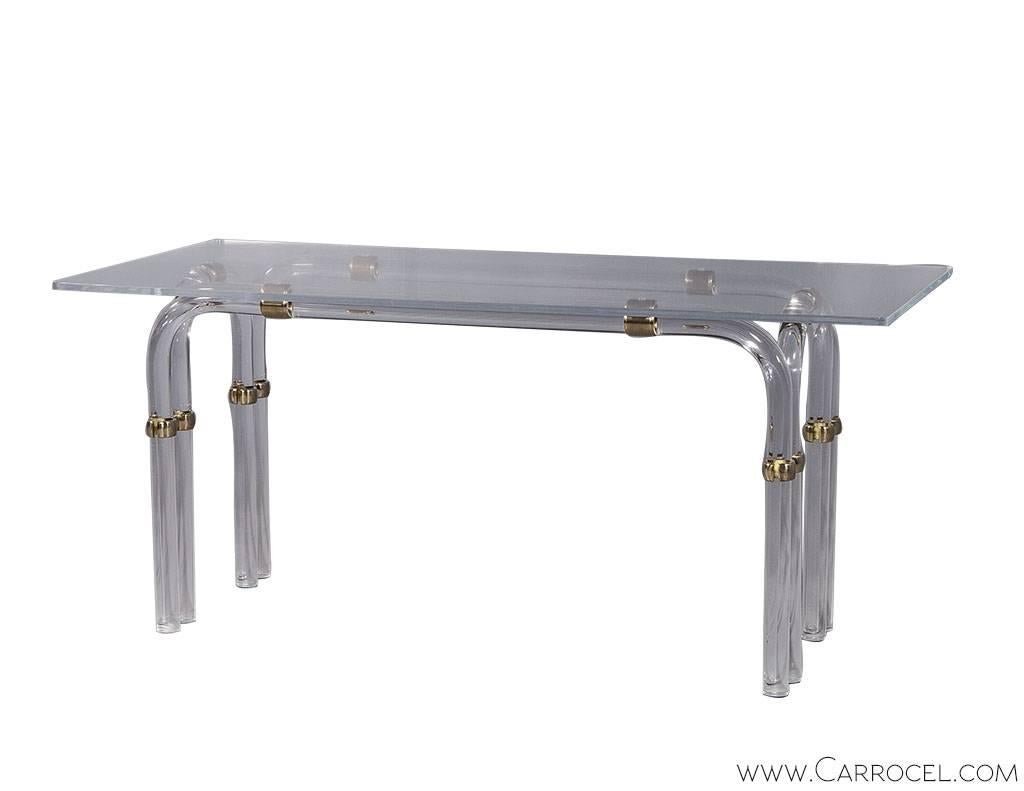 A gorgeous desk with a rectangular Lucite top floating on a base of cylindrical Lucite legs designed in a waterfall style, joined with brass mounts. Vintage style with a timeless design.