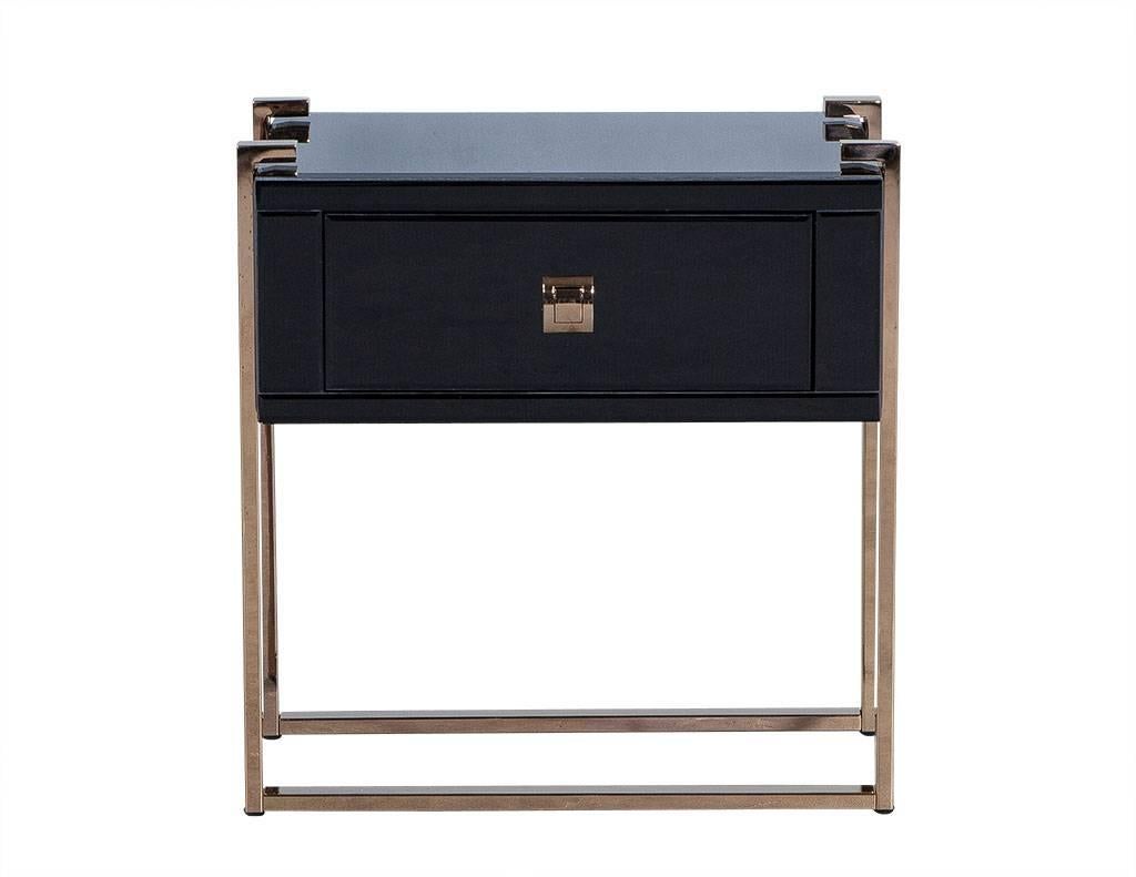 Sleek one-drawer nightstand encased in tempered, black glass. This nightstand lays atop dark copper finished stainless steel legs. Matching copper hardware completes the look. Sharp and chic, and a great addition to any trendy bedroom.