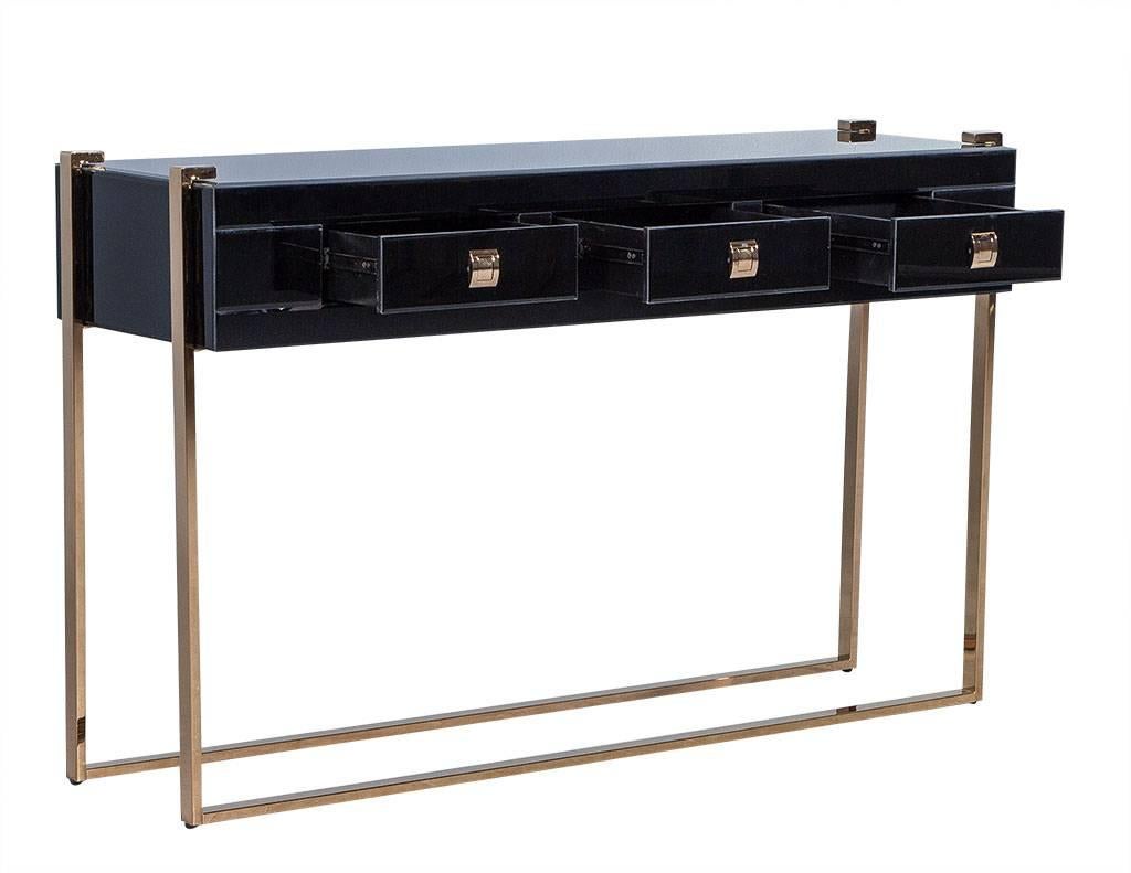 Sleek three-drawer console encased in thick, tempered, black glass. The dark copper finished stainless steel legs wrap continuously around the bottom and up into the glass top. A chic, sharp piece that would bring timeless class and style to any