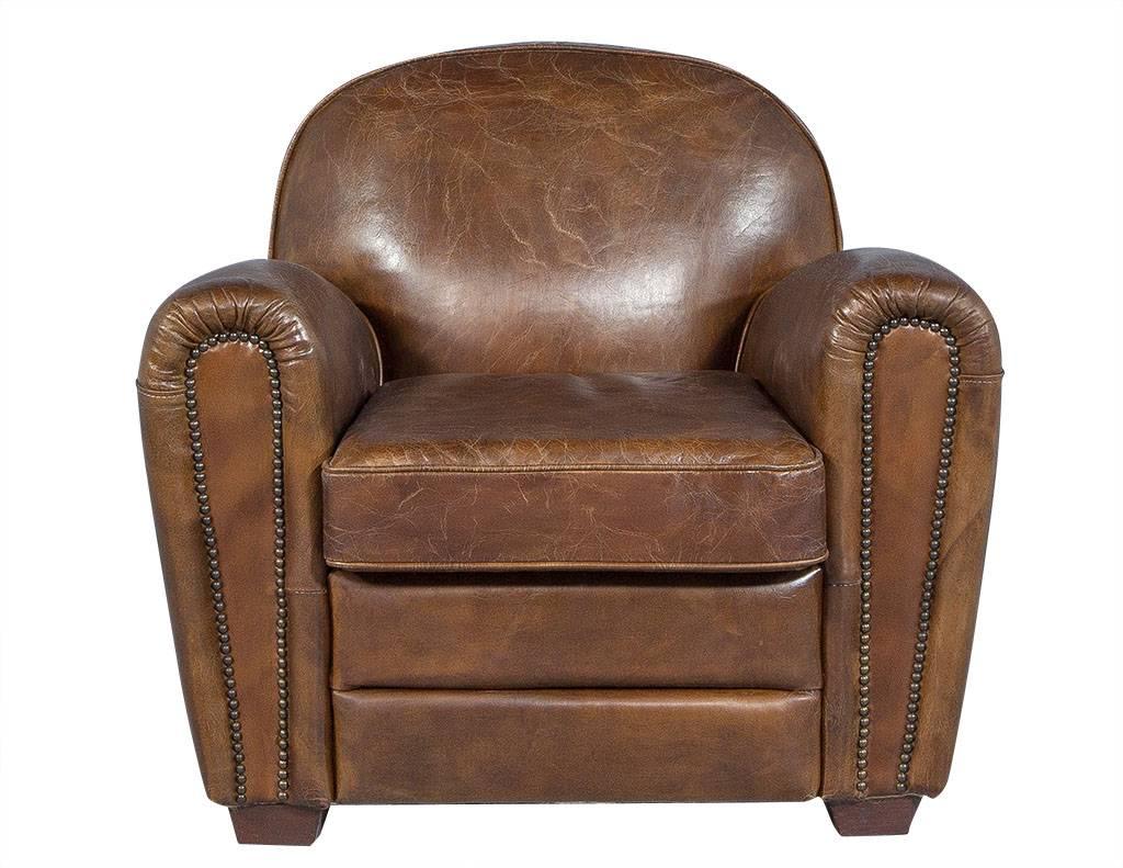 Handsome pair of chestnut-colored, distressed leather club chairs showcasing low backs and antiqued brass nailhead trim along the padded, rolled arms. Add Classic elegance to your living room with these plush and inviting chairs, perfect for