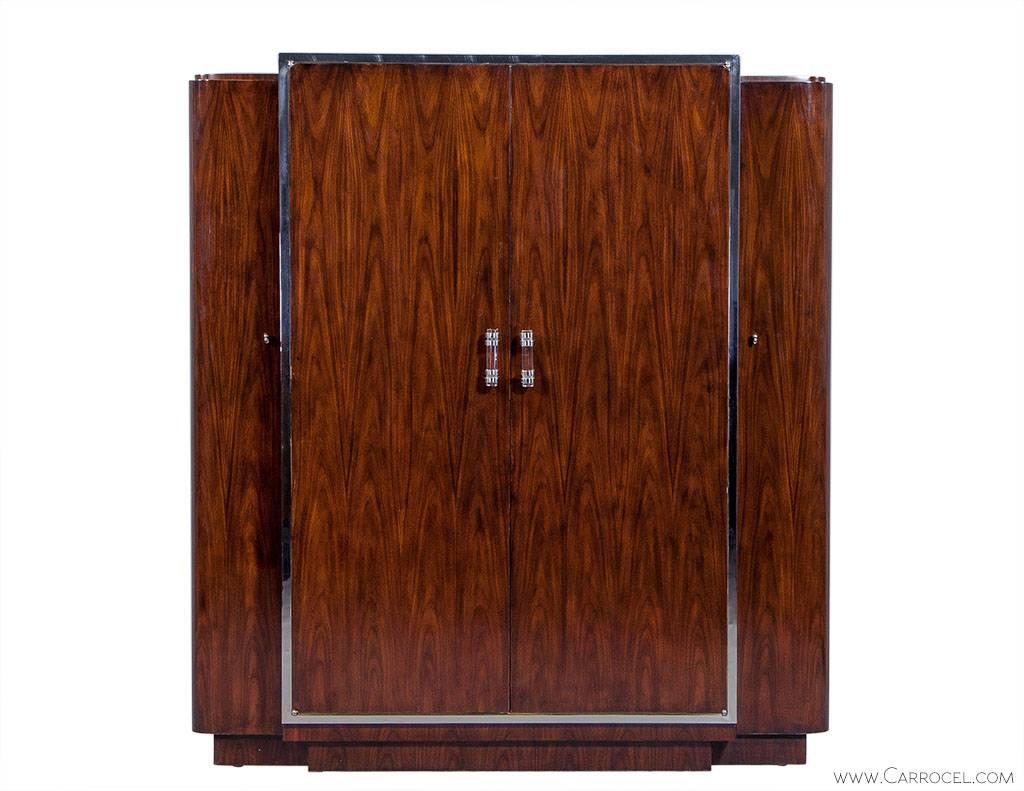 This Art Deco style wardrobe by Ralph Lauren is composed of strong mahogany in a penthouse rosewood finish. The two side compartments house shelves and hooks, while the one central compartment is accessible through double doors. This compartment