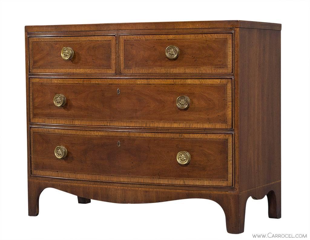 This Henredon 18th century Portfolio chest is an understated yet handsome piece made of mahogany with a bow front. Each drawer face is bordered in satinwood and is adorned with round, floral motif brass drawer pulls. There are also small, decorative