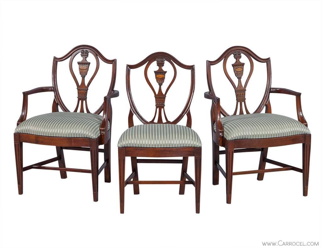 Gorgeous and newly restored, set of six mahogany dining chairs. Designed with finely crafted shield backs, intricately carved splats, tapered legs and striped blue-gold upholstery.

Dimensions:
Arm: H 38.5”, W 26”, D 23”, SH 20”.
Side: H 38.5”,
