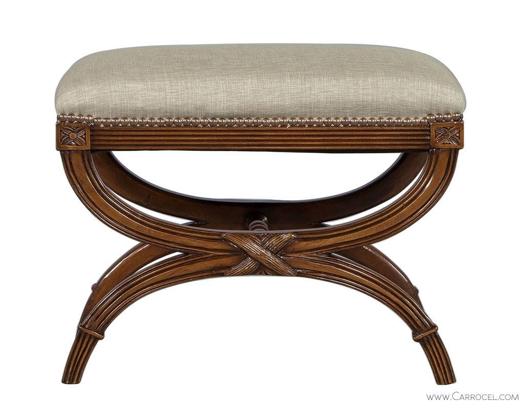 Louis XVI style ottoman with a cross brace hand-carved base, upholstered top and trimmed with head-to-head nails. Newly restored and reupholstered with a shimmery taupe designer fabric. Great little piece for the nook you are looking to fill.