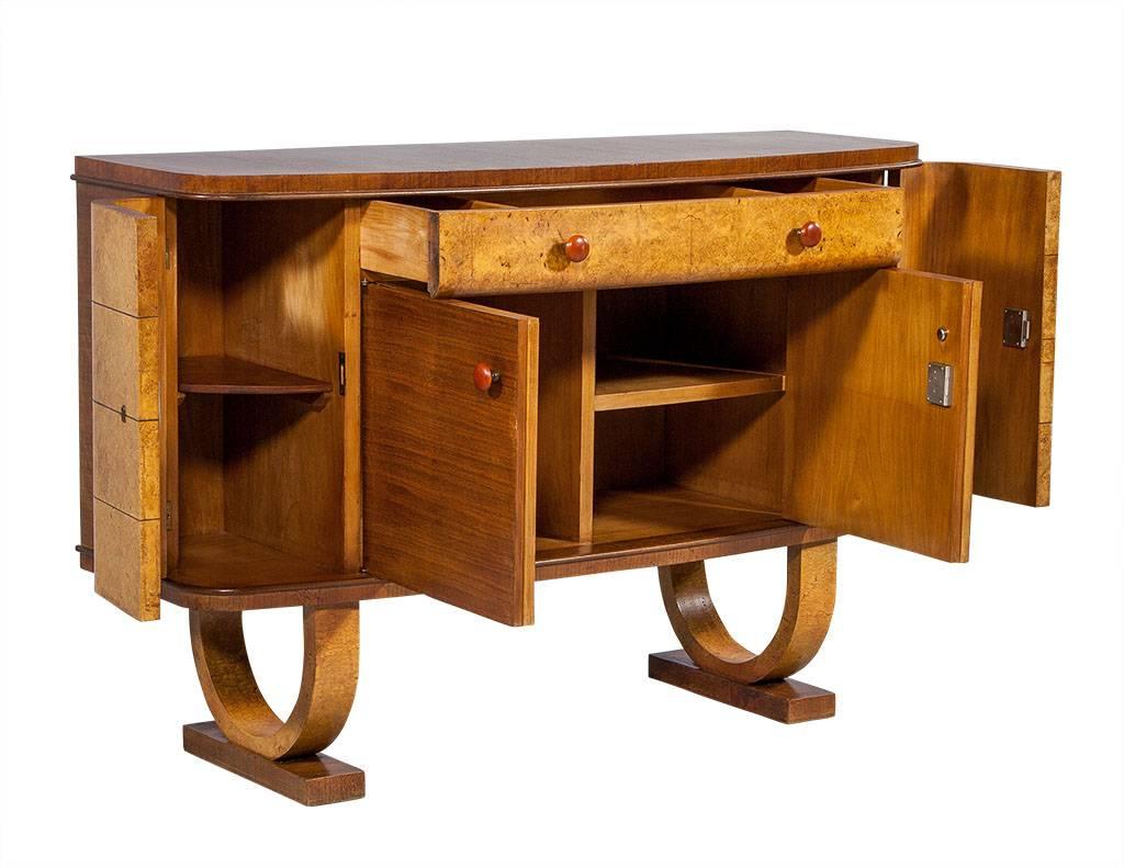 This unique buffet is enveloped in madrone burl veneer with contrasting mahogany and rich, amber colored knobs. There are two side compartments with shelving, a larger central compartment and two central drawers at the top for plenty of storage