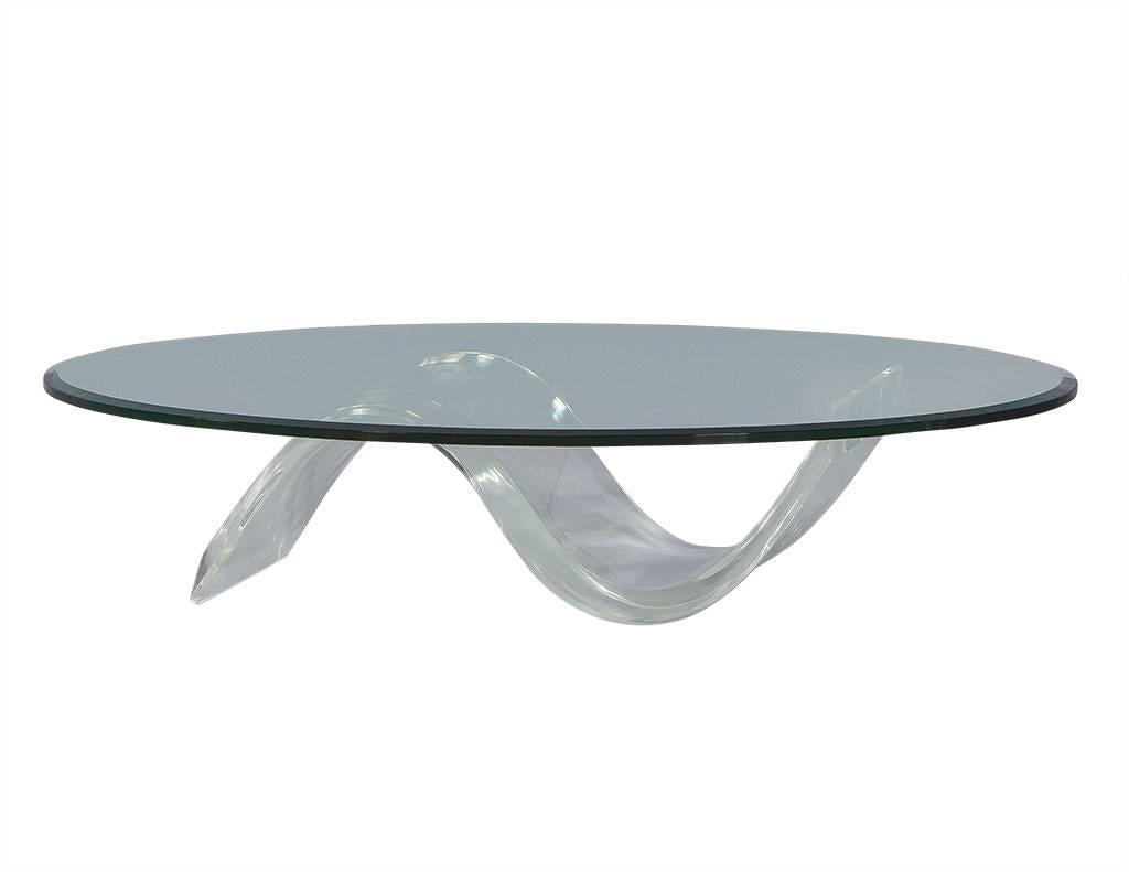 This Mid-Century style cocktail table is clearly a statement piece. The curved acrylic base has a beveled edge for added texture and is topped with a 1” thick piece of oval glass. At 11.5” tall, it is low enough to be used as a simplistic coffee
