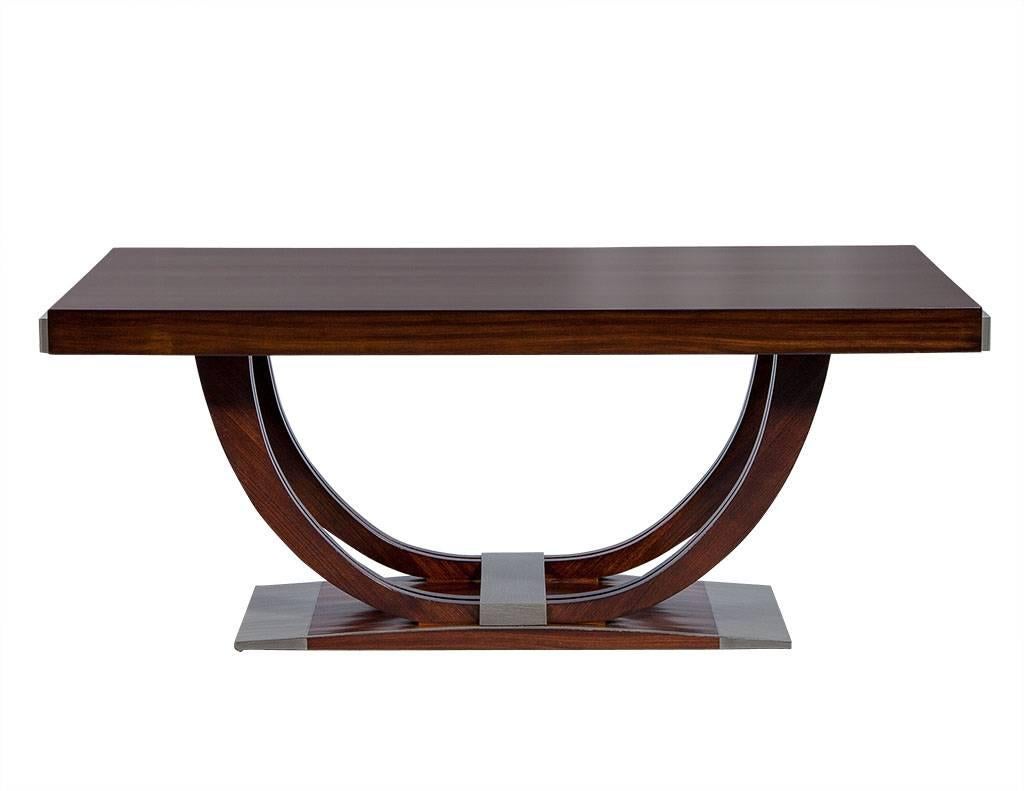 This is a stunning Art Deco table enveloped in rosewood veneers with rich textural slate grey accents. Designed in the Classic Deco aesthetic the centralized double ‘U’ pedestal supports a thick slab top with extension pulls on both sides to