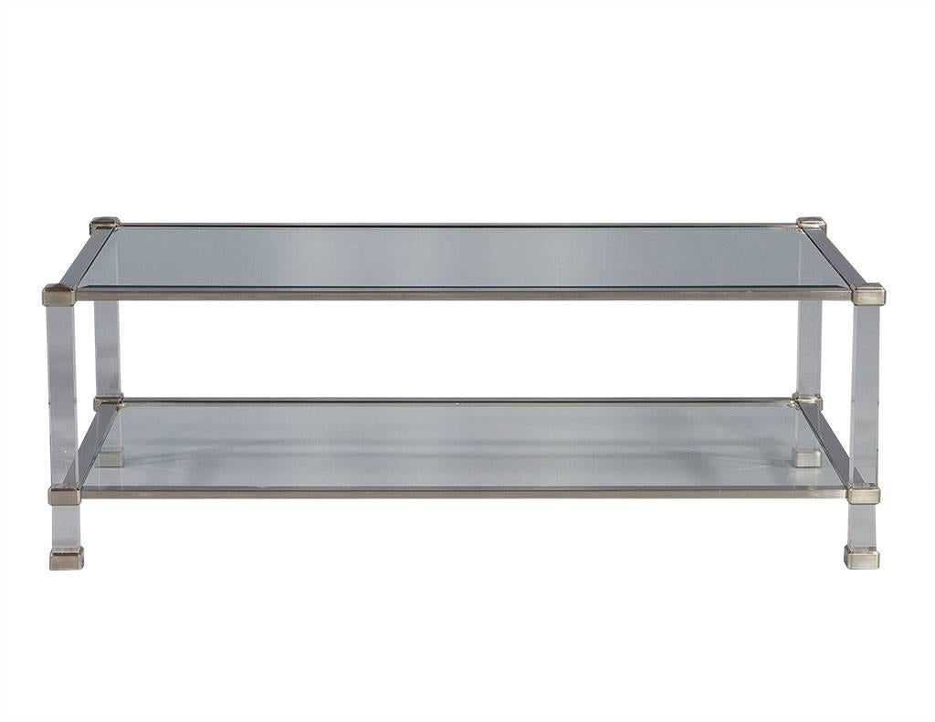 This stunning cocktail table is ideal for any Mid-Century Modern living space. Brushed chrome frames both the glass top and bottom shelf and there are acrylic supports in between and below. The clean lines and mixed media of this piece make it not