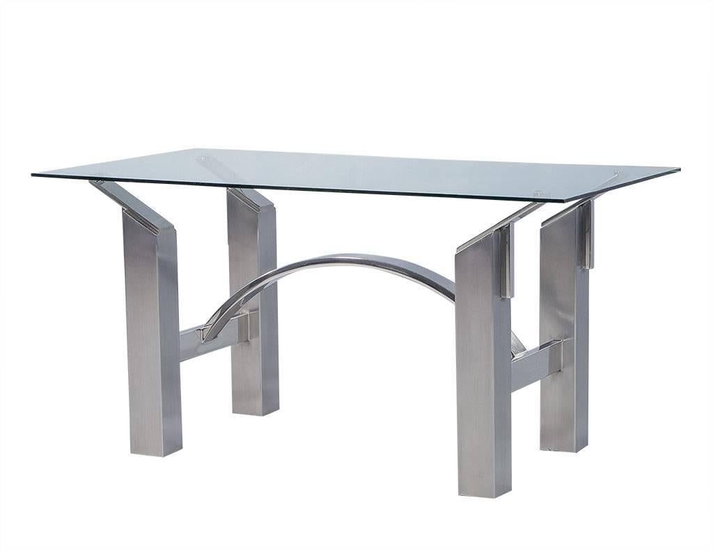 A strong architectural influence defines this table, seen from the shape through to the combination of materials: Polished nickel, brushed steel and glass. The base is built with four strong legs offset in each corn and a beautiful arch infusing an
