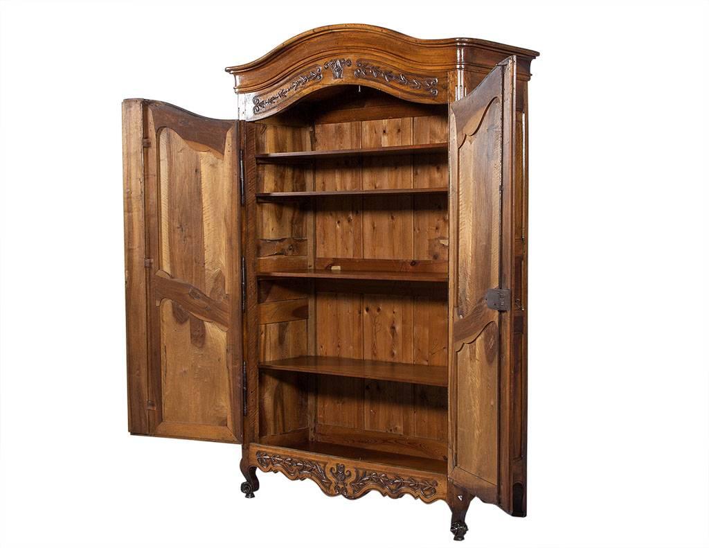 This Louis XV style armoire is made of walnut and has a rich, glowing patina, hand-carved motifs and a central fluted pilaster between the doors. It sits atop cabriole legs with escargot feet and showcases more beautiful details within the iron
