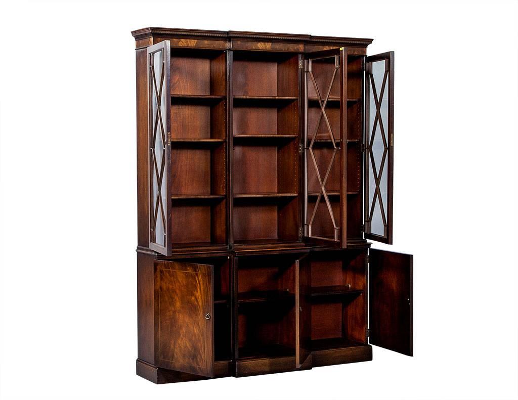 This English style china cabinet is crafted out of rich mahogany. It has three breakfront glass panels on the upper cabinets with 12 interior shelves for display and the lower compartment includes six interior shelves concealed by three doors. The