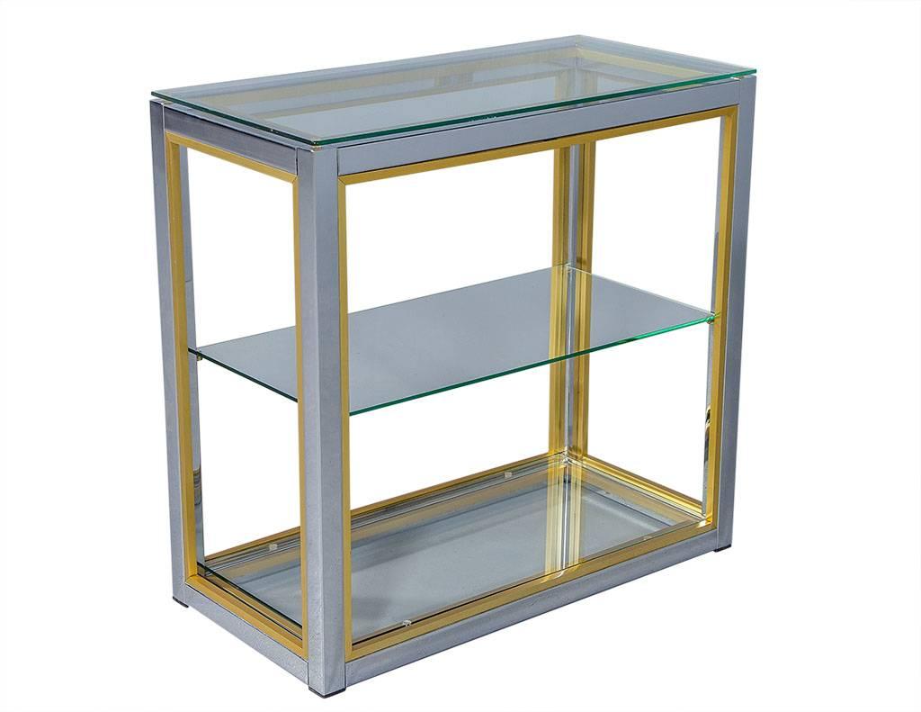 This Mid-Century Modern etagere is attributed to Renato Zevi and embodies Italian style and elegance. It has a polished chrome frame with brushed brass trim and three glass shelves perfect for displaying your trinkets. It is the perfect addition to