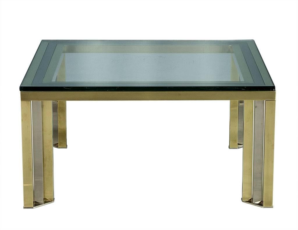 This Mid-Century Modern cocktail table is both elegant and futuristic. The design is attributed to Romeo Rega and it is comprised of polished brass and chrome legs top with a thick slab of glass. This piece is sharp enough to truly make a statement