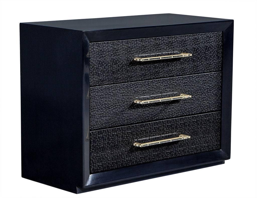 These beautifully Classic wooden chests are manufactured by John Stuart. They have a concave border on the outer parameter with an ostrich pattern leatherette covering the drawers and are adorned with satin brass and acrylic hardware. The finish is