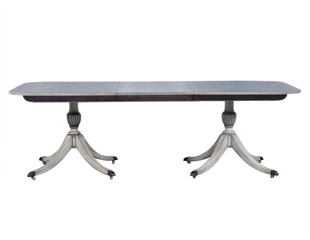 This dazzling dining table is attributed to Duncan Phyfe and lends to a distinctive English style. It is crafted out of solid, bleached mahogany with satinwood banding and finished in a satin translucent dove grey stain. The pedestal is made of