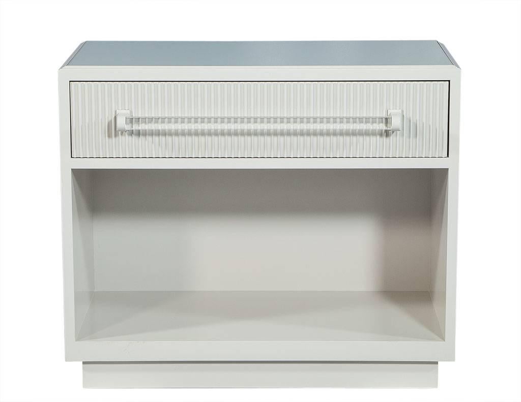 This transitional style chest is wonderfully fresh and intrinsically modern. Made to order right here in Canada, crafted of solid wood and finished in eggshell white with long Lucite tubular handles and an inlaid glass top with beveled edges. This