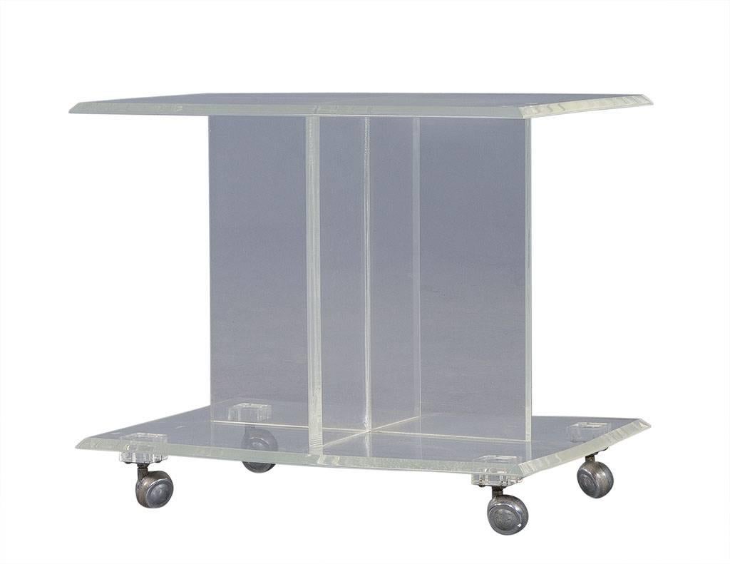 This Mid-Century Modern accent table is comprised of clean Lucite atop sharp metal castors. With a geometric center base and rectangular top and bottom, this piece is certainly unique and a great addition to any bedroom!