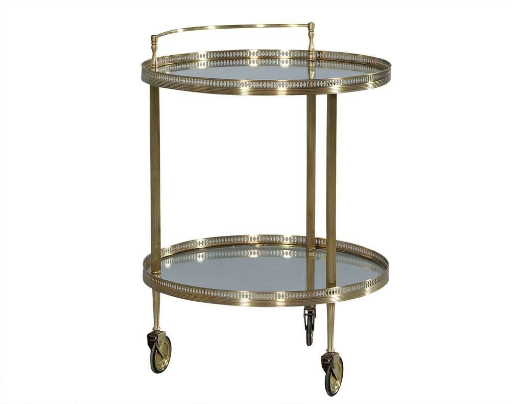 This Art Deco style bar cart is absolutely divine. Crafted out of round polished brass with two glass shelves, it sits atop three wheels with a handle on the upper shelf and a stenciled banding around both. Perfect for making whatever beverage