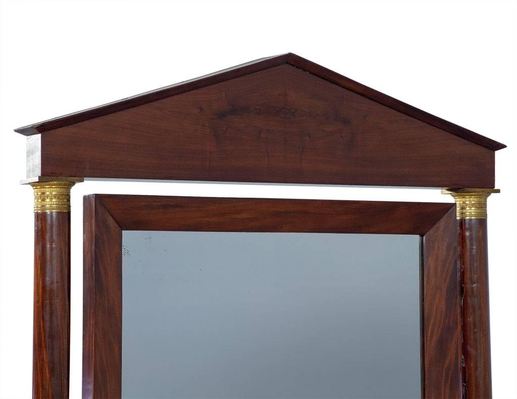 This gorgeous, French empire style mirror is cased in mahogany with a center point tilt.  With brass accents, small castors on four arched legs and a peaked arched top, this circa 60’s cheval mirror oozes character and elegance.