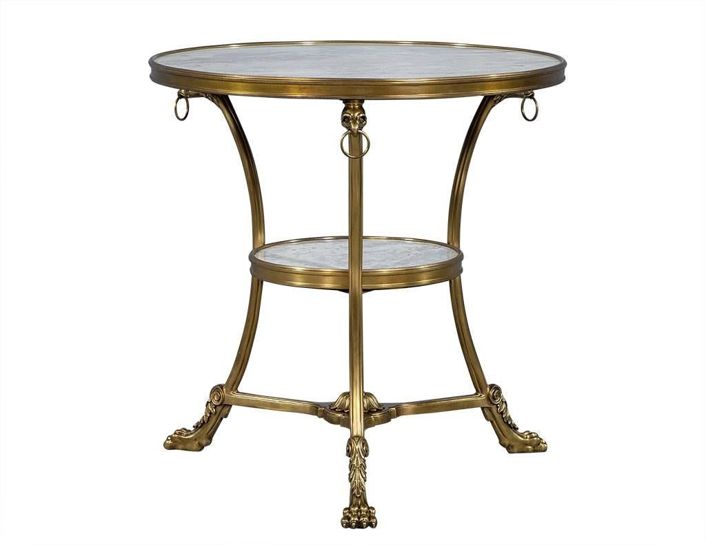 These neoclassical side tables are a gorgeous piece of antiquity.  They are comprised of two tiers with grey and white marble slabs and a satin brass base decorated with bear claw feet and ostrich heads along the top edge.  The three feet are