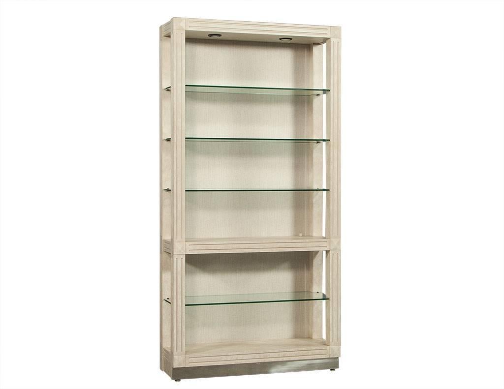 This Transitional style bookcase is just plain lovely. It is crafted out of beechwood with reeding along the frame and a polished nickel base and trim. It consists of five shelves, four which are glass, and an upholstered interior back panel with