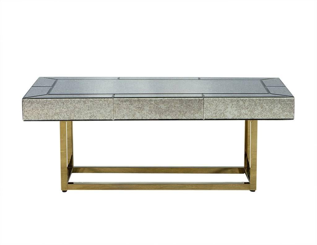 This Mid-Century Modern cocktail table is a lesson in glamour. It has a gorgeous antique mirror glass top consisting of panels on the parameter of the table sitting atop a stainless steel base finished in gold. A perfect fit for a glitzy living room.