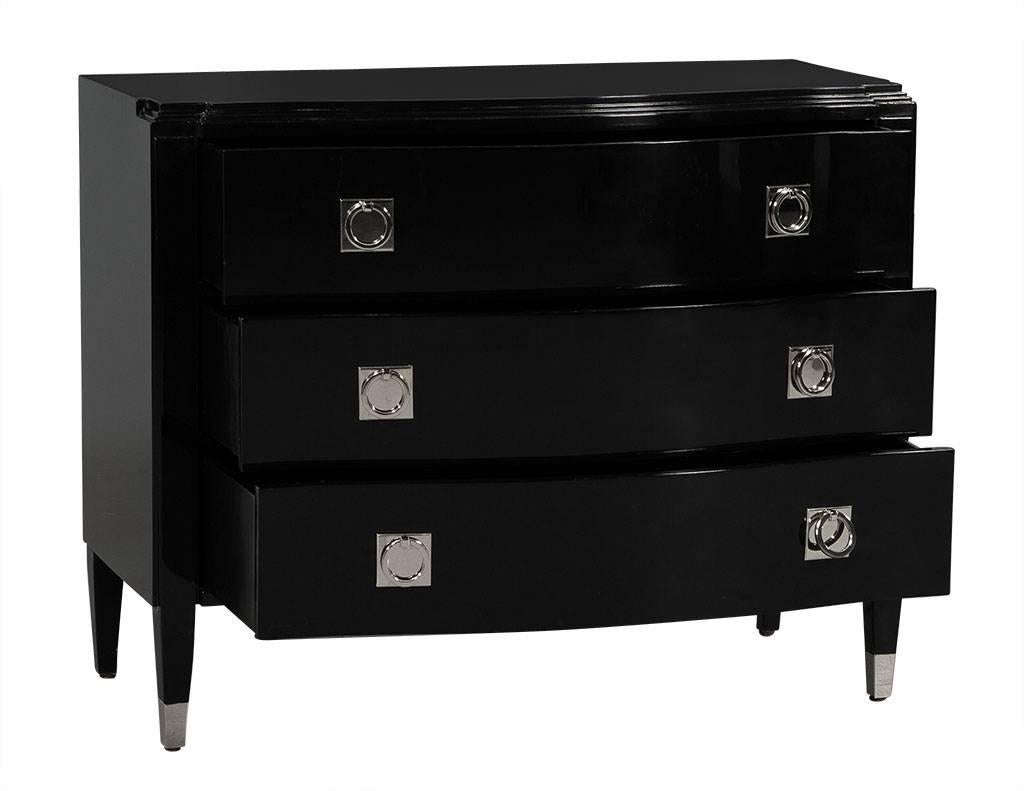This transitional style chest has three drawers and is finished in a rich, black lacquer. It features a serpentine top and bit of glitz with stainless steel ferrule pulls. The piece sits atop four fluted legs with stainless steel caps on the two