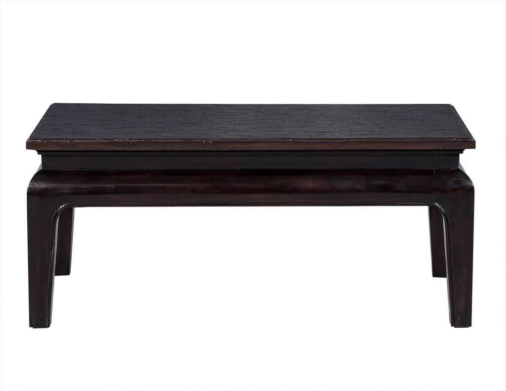 This Hollywood Regency style cocktail table is crafted out of beechwood with an ebonized finish. The top is antique blackwash and rustic in texture, giving it a luxurious yet simple character to add to your living area.