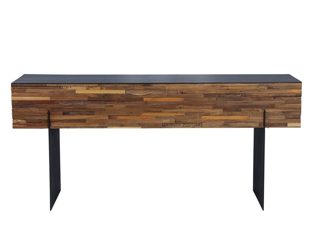 This Mid-Century Modern console is a beautifully rustic piece. It is crafted out of medium cherry reclaimed wood pieces assembled in an interlocking fashion with a walnut wood top and two horizontal metal panels as the base. A perfect fit for a