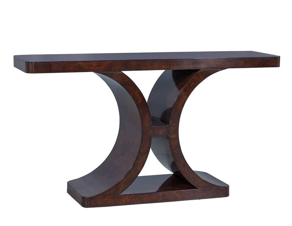 This Art Deco style console is a classy and unique piece. It is crafted out of burled walnut wood finished in a sterling walnut and accented with an Art Deco style base. A perfect fit for a gorgeous entryway!