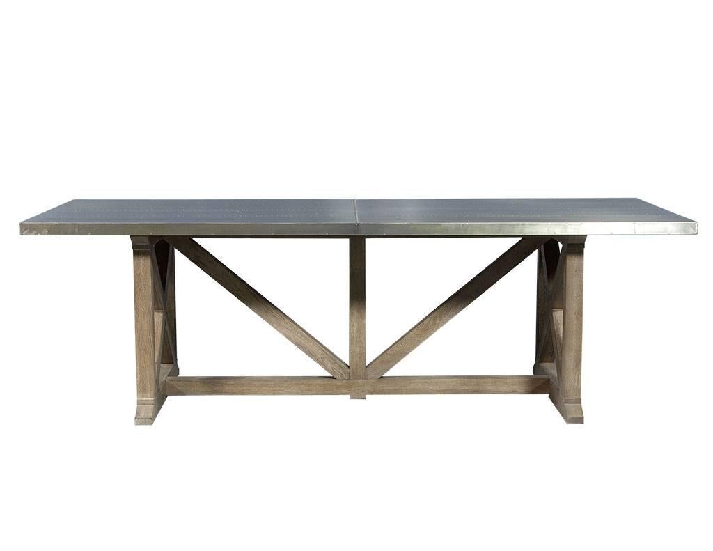 This transitional style dining table is the perfect mix of rustic and Industrial. It is comprised of a riveted, antique metal-panel sitting atop a driftwood grey wood crate base. A beautiful piece that adds some character to any dining room.