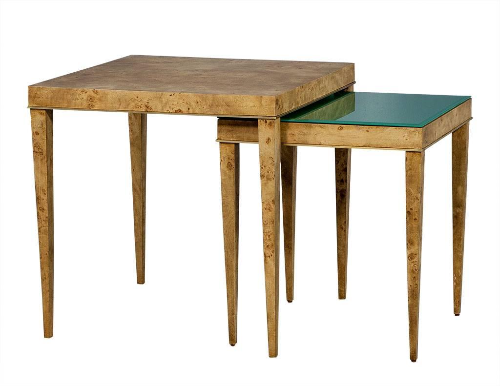 Set of square burled walnut nesting tables with natural finish. Features brass trim along lower tabletop edge and sits upon long fluted legs. Smaller table is accented with green beveled glass that covers the entirety of the top.

Larger table: H