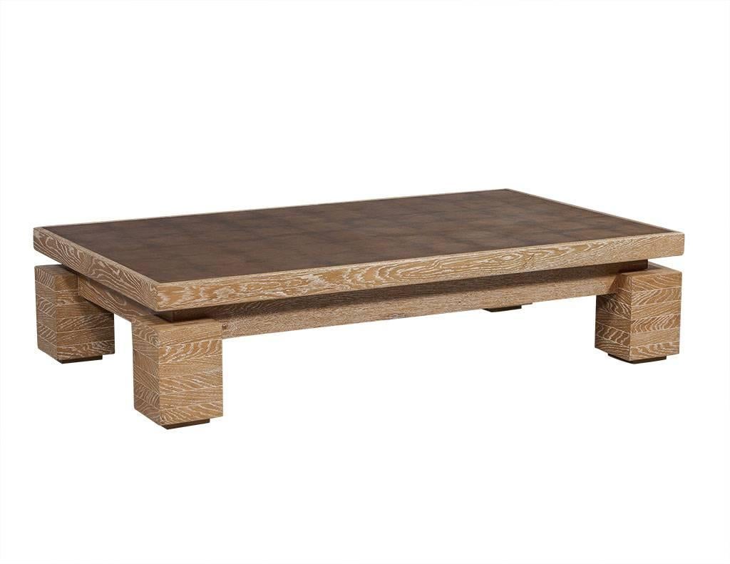 This rustic yet modern coffee table is made of cerused oakwood with a natural finish. Staked square wood panels act as supports while the top features a gold canvas square-pattern.