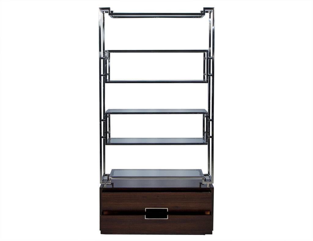 This American designed étagère features a geometric stainless steel frame that supports six floating glass shelves. The gorgeous Macassar Ebony base includes two drawers accented with stainless steel pulls. A modern yet timeless addition to any room!
