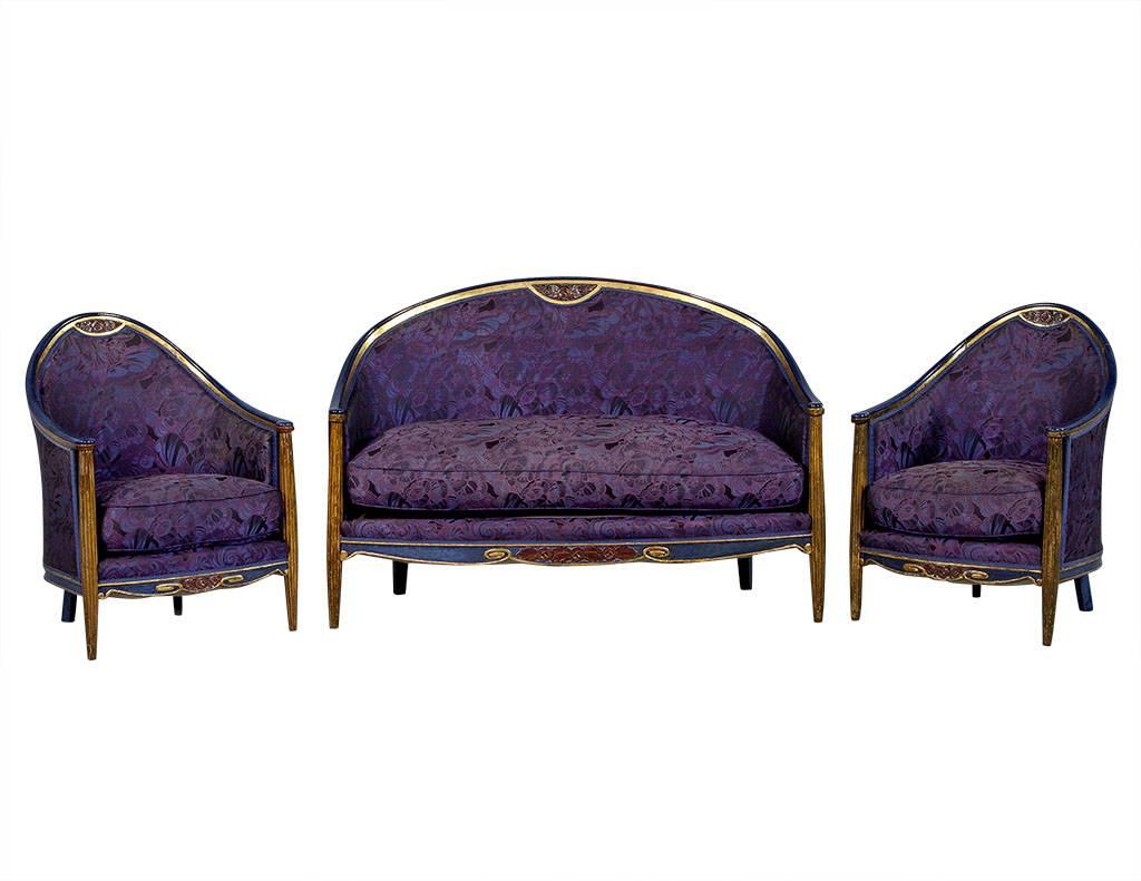 This Art Deco style salon set is in the style of Paul Follot. The set includes a settee, two tub chairs and two petite side chairs. The frames are made out of hand-carved show wood and are finished with a deep blue gilded detail. The upholstery is a
