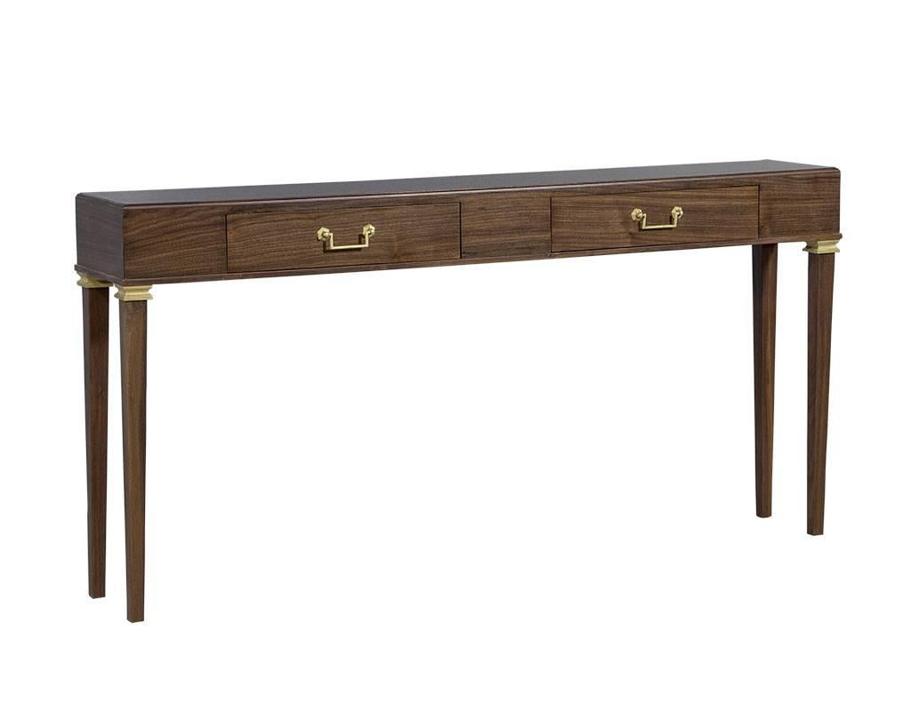This traditional style console is sleek and stylish. Crafted out of solid oak with two front facing drawers, this piece is accented with brass handles and hand-painted detail on the top of the fluted legs. The finish is a warm brown stain, making
