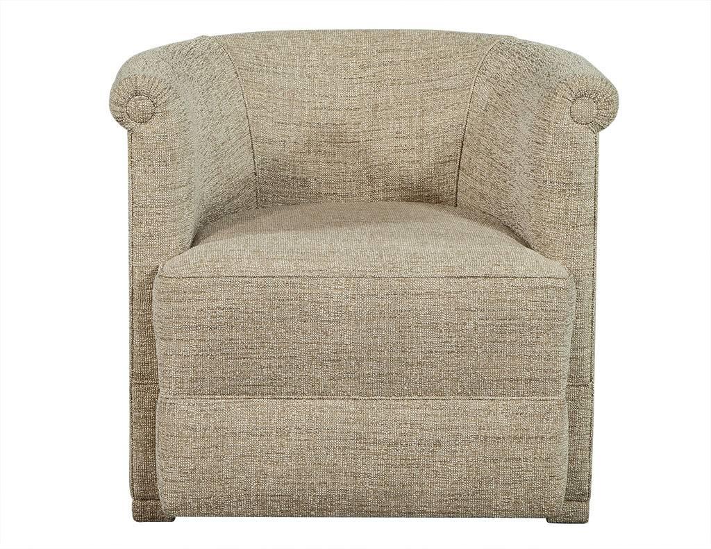 This traditional tub chair is a comforting, Classic piece. It is fully upholstered in a textured, woven, wheat-colored fabric with a curved back and single decorative button on the ends of the arm rests. A soft, warm piece perfect for any sitting